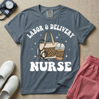 A Labor and Delivery nurse graphic featuring a large beige tote bag with a leopard print pocket, a stethoscope draped over it, and a large iced coffee cup with a matching leopard print sleeve, all surrounded by white text that reads LABOR & DELIVERY curved above and NURSE below.