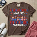 A cute Neonatal Intensive Care Unit nurse graphic featuring a row of diverse babies wrapped in patriotic red, white, and blue star-spangled and striped swaddles, with some wearing top hats, surrounded by fireworks and star bunting, alongside retro text reading CARING FOR THE Cutest little FIRECRACKERS NICU NURSE.