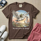 A humorous Labor and Delivery graphic featuring a storybook illustration of a frog dressed as a knight wielding a sword, riding on the back of a flying stork that is carrying a sleeping baby in a bundle, soaring over a fantasy landscape with a castle at sunrise, accompanied by text below that reads We deliver at dawn.