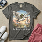 A humorous Labor and Delivery graphic featuring a storybook illustration of a frog dressed as a knight wielding a sword, riding on the back of a flying stork that is carrying a sleeping baby in a bundle, soaring over a fantasy landscape with a castle at sunrise, accompanied by text below that reads We deliver at dawn.