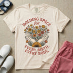A Labor and Delivery and Doula graphic featuring an illustration of two open hands gently holding a bouquet of wildflowers with a large sunflower at the base, surrounded by white text that reads HOLDING SPACE for above and EVERY BIRTH. EVERY BODY. below.