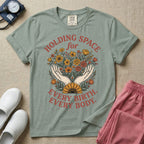 A Labor and Delivery and Doula graphic featuring an illustration of two open hands gently holding a bouquet of wildflowers with a large sunflower at the base, surrounded by white text that reads HOLDING SPACE for above and EVERY BIRTH. EVERY BODY. below.