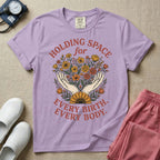 A Labor and Delivery and Doula graphic featuring an illustration of two open hands gently holding a bouquet of wildflowers with a large sunflower at the base, surrounded by white text that reads HOLDING SPACE for above and EVERY BIRTH. EVERY BODY. below.