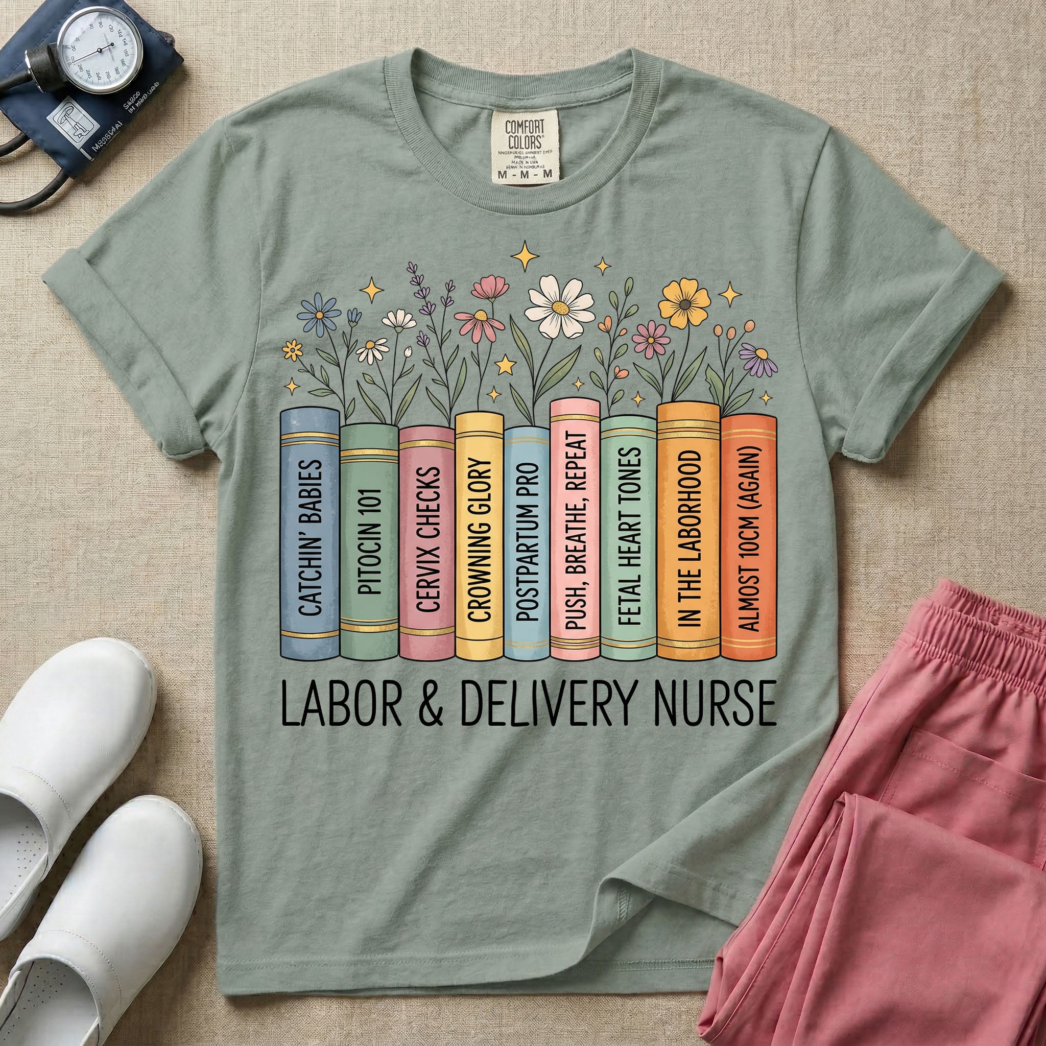 A Labor and Delivery nurse graphic featuring a row of standing books with colorful wildflowers blooming from the top pages. The book spines feature humorous titles reading CATCHIN' BABIES, PITOCIN 101, CERVIX CHECKS, CROWNING GLORY, POSTPARTUM PRO, PUSH, BREATHE, REPEAT, FETAL HEART TONES, IN THE LABORHOOD, and ALMOST 10CM (AGAIN), with the text LABOR & DELIVERY NURSE written directly below.
