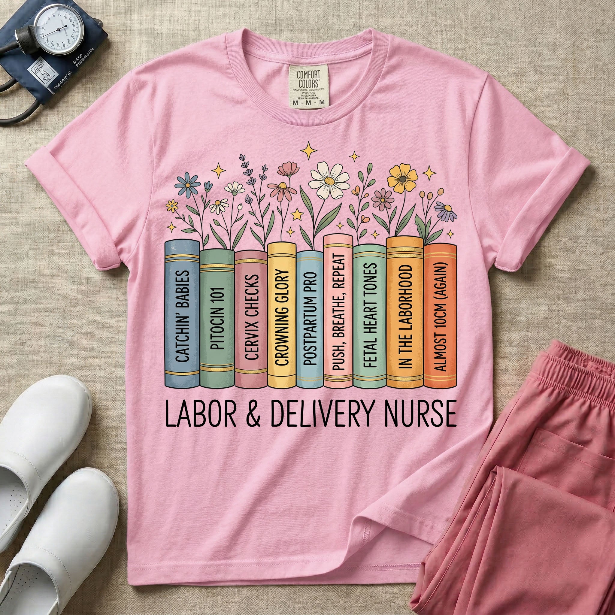 A Labor and Delivery nurse graphic featuring a row of standing books with colorful wildflowers blooming from the top pages. The book spines feature humorous titles reading CATCHIN' BABIES, PITOCIN 101, CERVIX CHECKS, CROWNING GLORY, POSTPARTUM PRO, PUSH, BREATHE, REPEAT, FETAL HEART TONES, IN THE LABORHOOD, and ALMOST 10CM (AGAIN), with the text LABOR & DELIVERY NURSE written directly below.