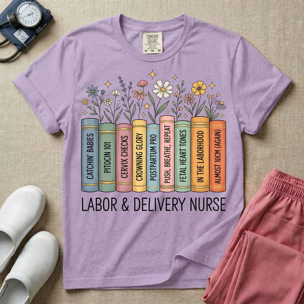 A Labor and Delivery nurse graphic featuring a row of standing books with colorful wildflowers blooming from the top pages. The book spines feature humorous titles reading CATCHIN' BABIES, PITOCIN 101, CERVIX CHECKS, CROWNING GLORY, POSTPARTUM PRO, PUSH, BREATHE, REPEAT, FETAL HEART TONES, IN THE LABORHOOD, and ALMOST 10CM (AGAIN), with the text LABOR & DELIVERY NURSE written directly below.