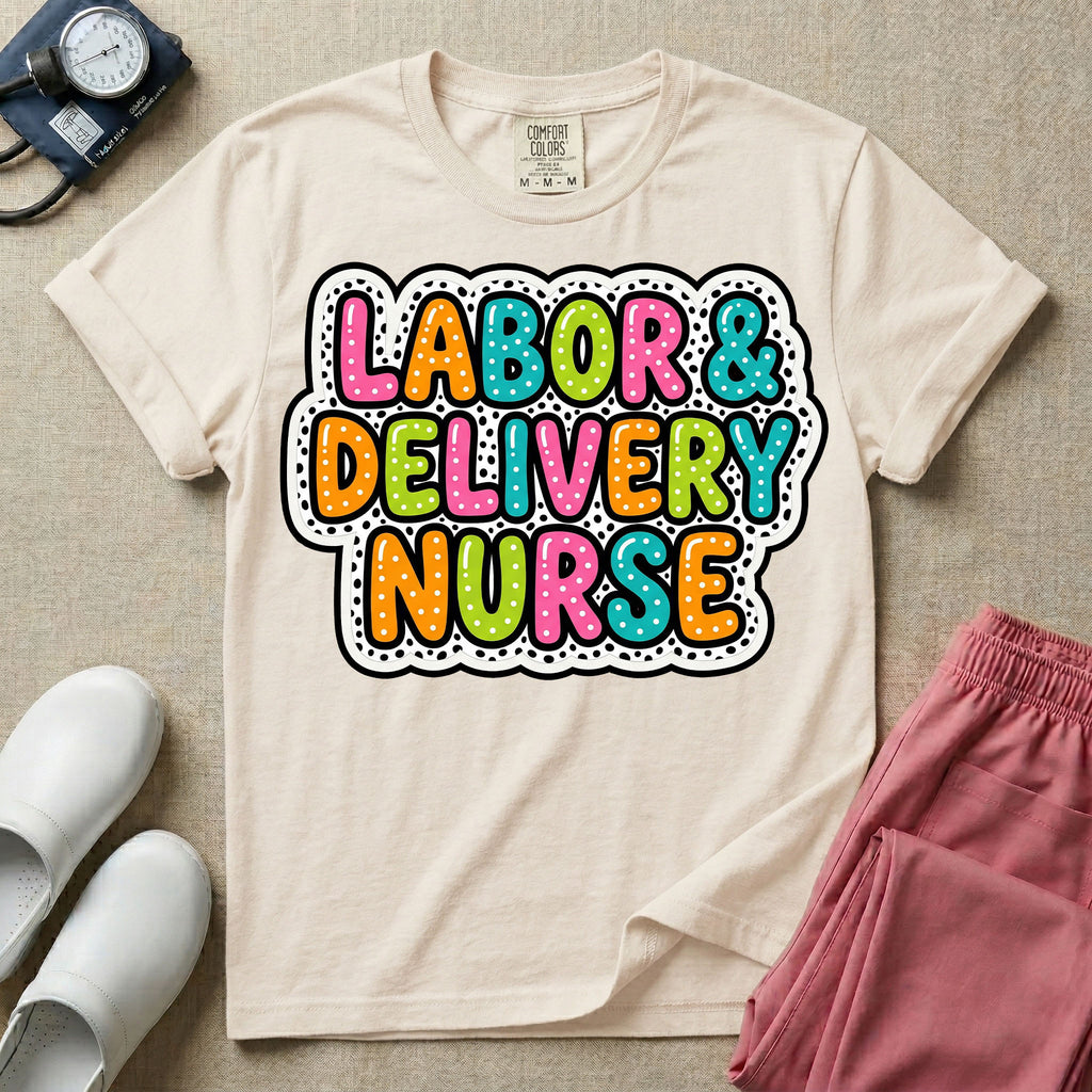 A graphic t-shirt for a Labor and Delivery unit featuring the text 'LABOR & DELIVERY NURSE' in bright, multicolored bubble lettering with white dots, framed by a contrasting black and white spotted background pattern.