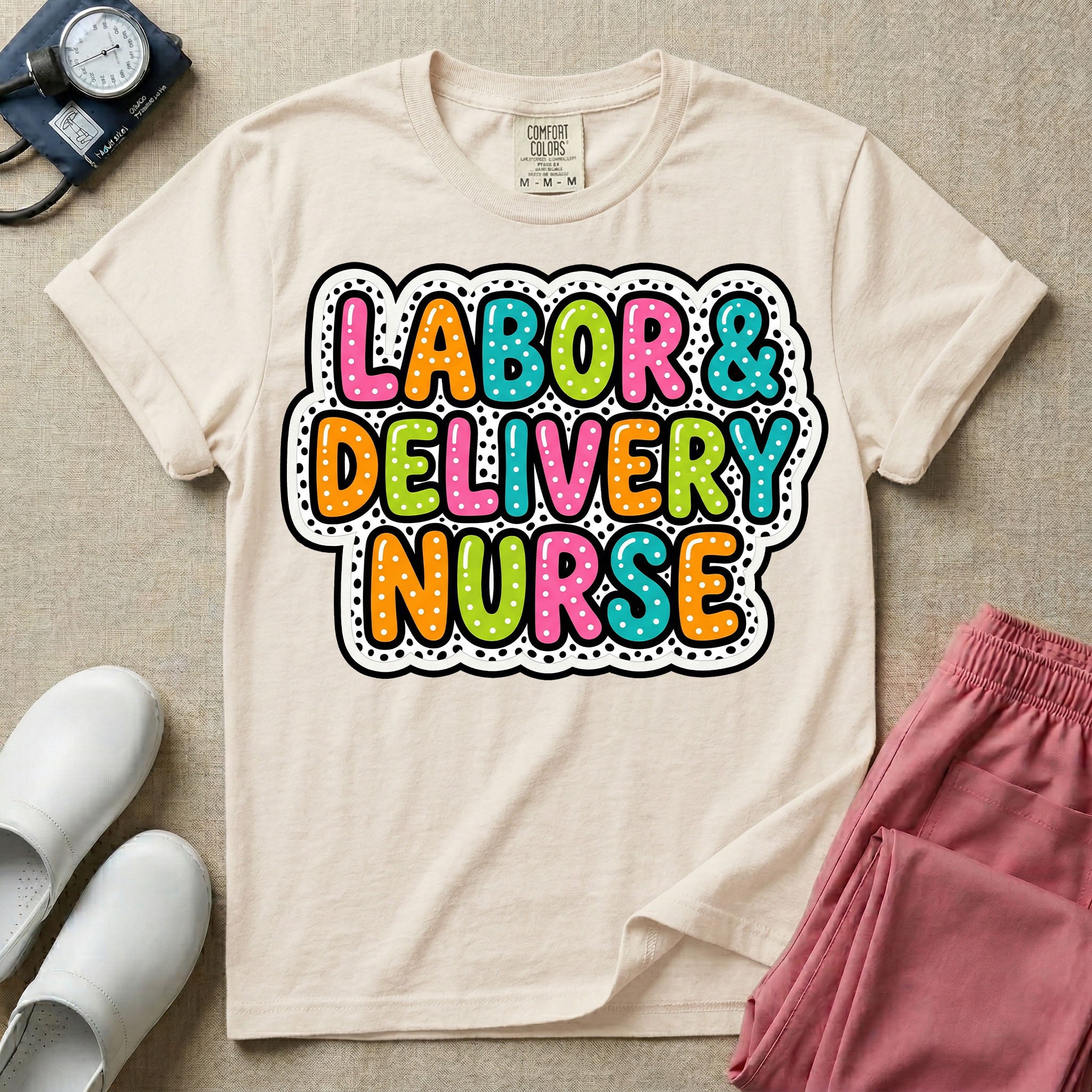 A graphic t-shirt for a Labor and Delivery unit featuring the text 'LABOR & DELIVERY NURSE' in bright, multicolored bubble lettering with white dots, framed by a contrasting black and white spotted background pattern.
