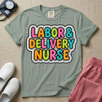 A graphic t-shirt for a Labor and Delivery unit featuring the text 'LABOR & DELIVERY NURSE' in bright, multicolored bubble lettering with white dots, framed by a contrasting black and white spotted background pattern.