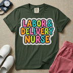 A graphic t-shirt for a Labor and Delivery unit featuring the text 'LABOR & DELIVERY NURSE' in bright, multicolored bubble lettering with white dots, framed by a contrasting black and white spotted background pattern.
