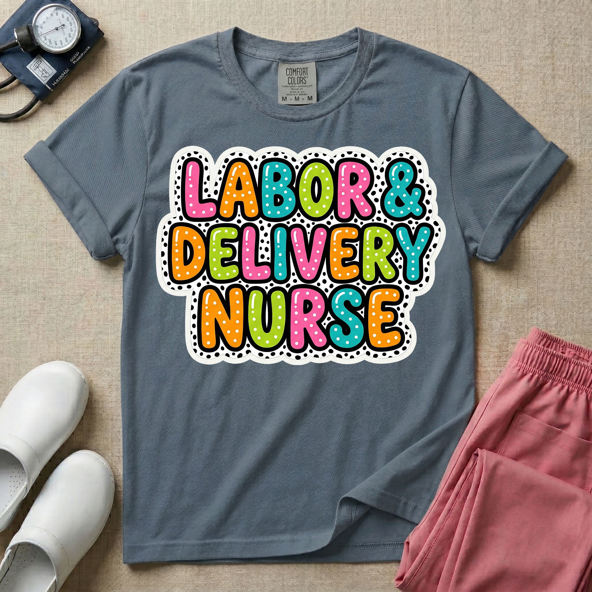 A graphic t-shirt for a Labor and Delivery unit featuring the text 'LABOR & DELIVERY NURSE' in bright, multicolored bubble lettering with white dots, framed by a contrasting black and white spotted background pattern.