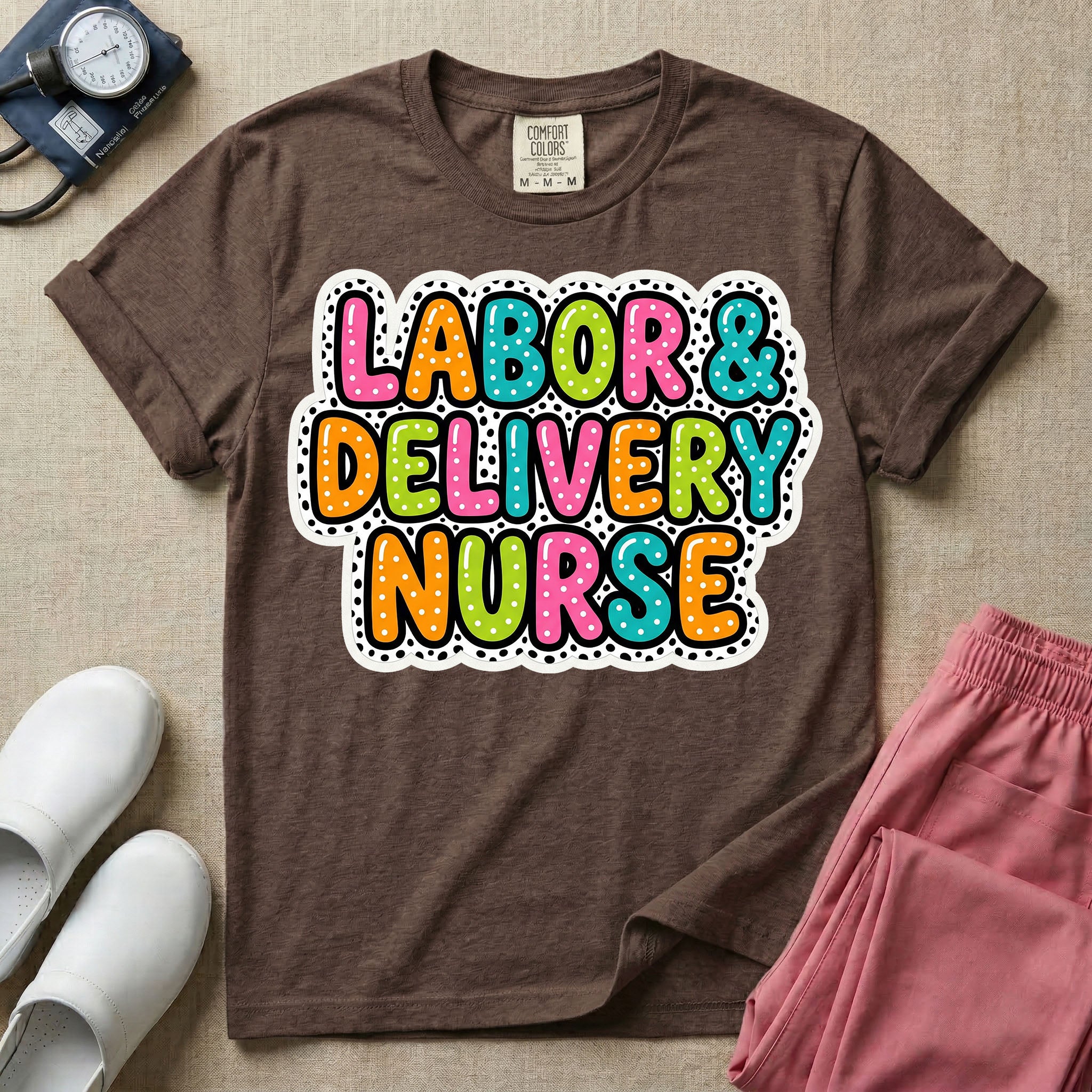 A graphic t-shirt for a Labor and Delivery unit featuring the text 'LABOR & DELIVERY NURSE' in bright, multicolored bubble lettering with white dots, framed by a contrasting black and white spotted background pattern.