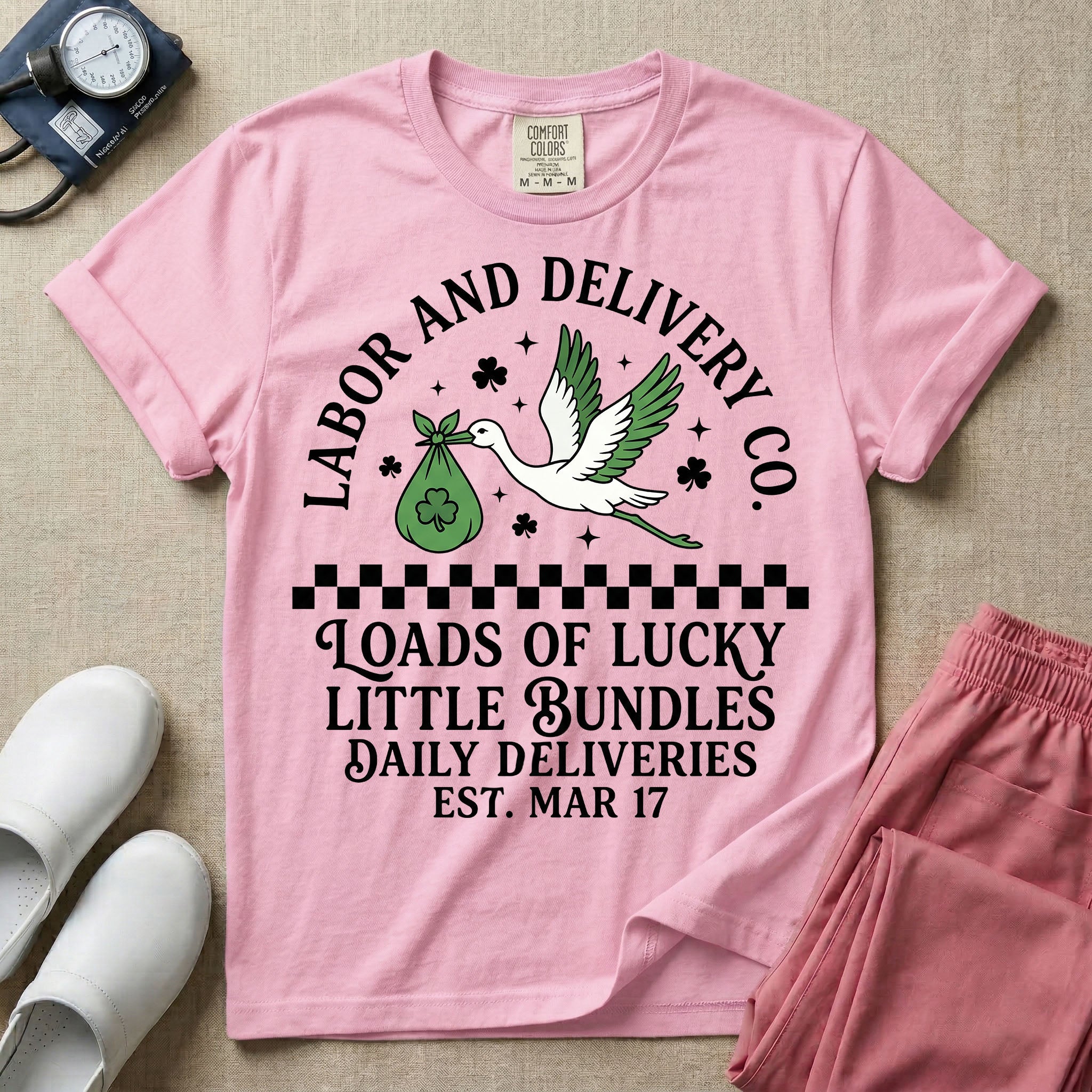 A retro Labor and Delivery nurse design featuring a flying stork carrying a sack with a shamrock, surrounded by stars and clovers, above a checkered border and the text "Labor and Delivery Co. Loads Of Lucky Little Bundles Daily Deliveries Est. Mar 17".
