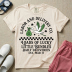 A retro Labor and Delivery nurse design featuring a flying stork carrying a sack with a shamrock, surrounded by stars and clovers, above a checkered border and the text "Labor and Delivery Co. Loads Of Lucky Little Bundles Daily Deliveries Est. Mar 17".