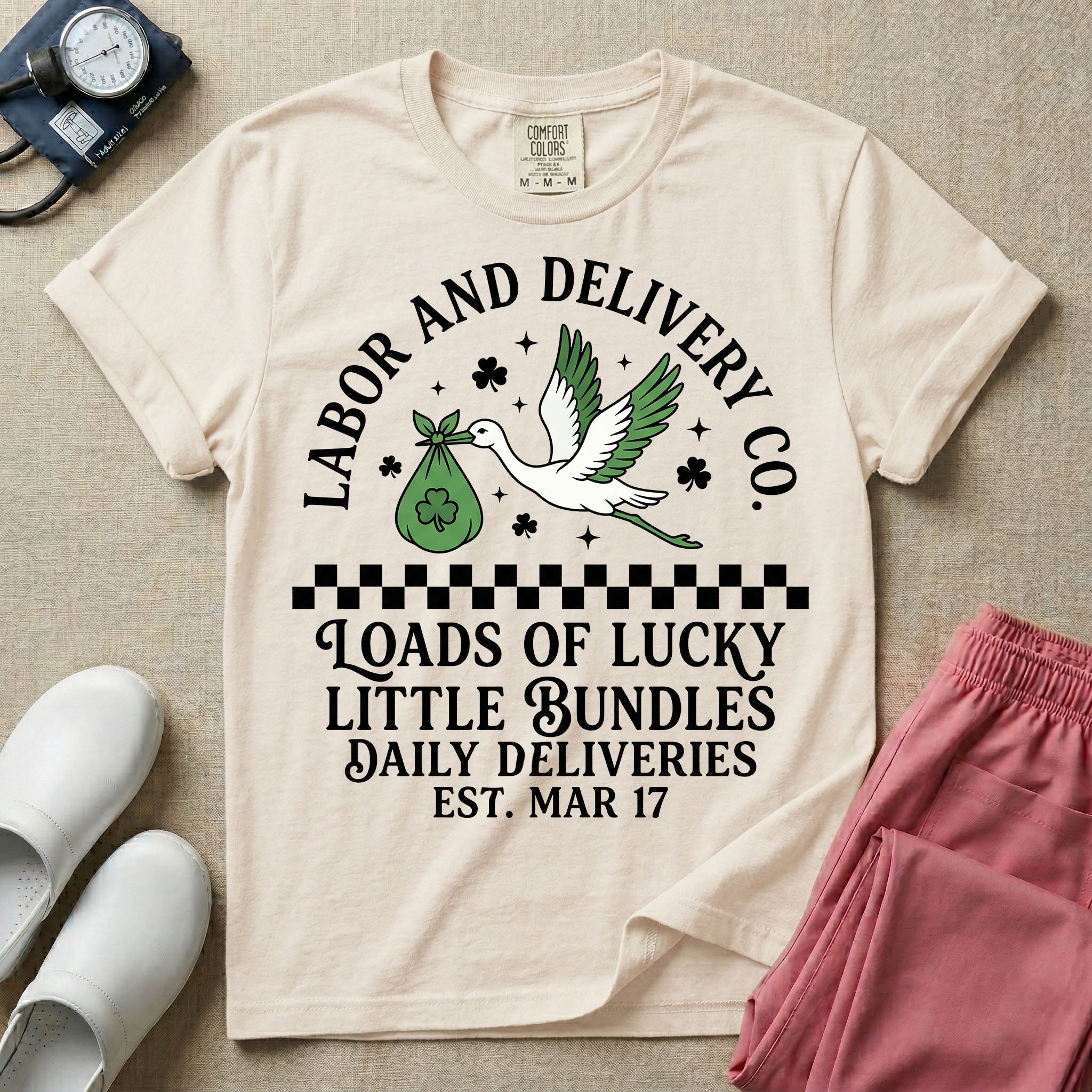 A retro Labor and Delivery nurse design featuring a flying stork carrying a sack with a shamrock, surrounded by stars and clovers, above a checkered border and the text "Labor and Delivery Co. Loads Of Lucky Little Bundles Daily Deliveries Est. Mar 17".