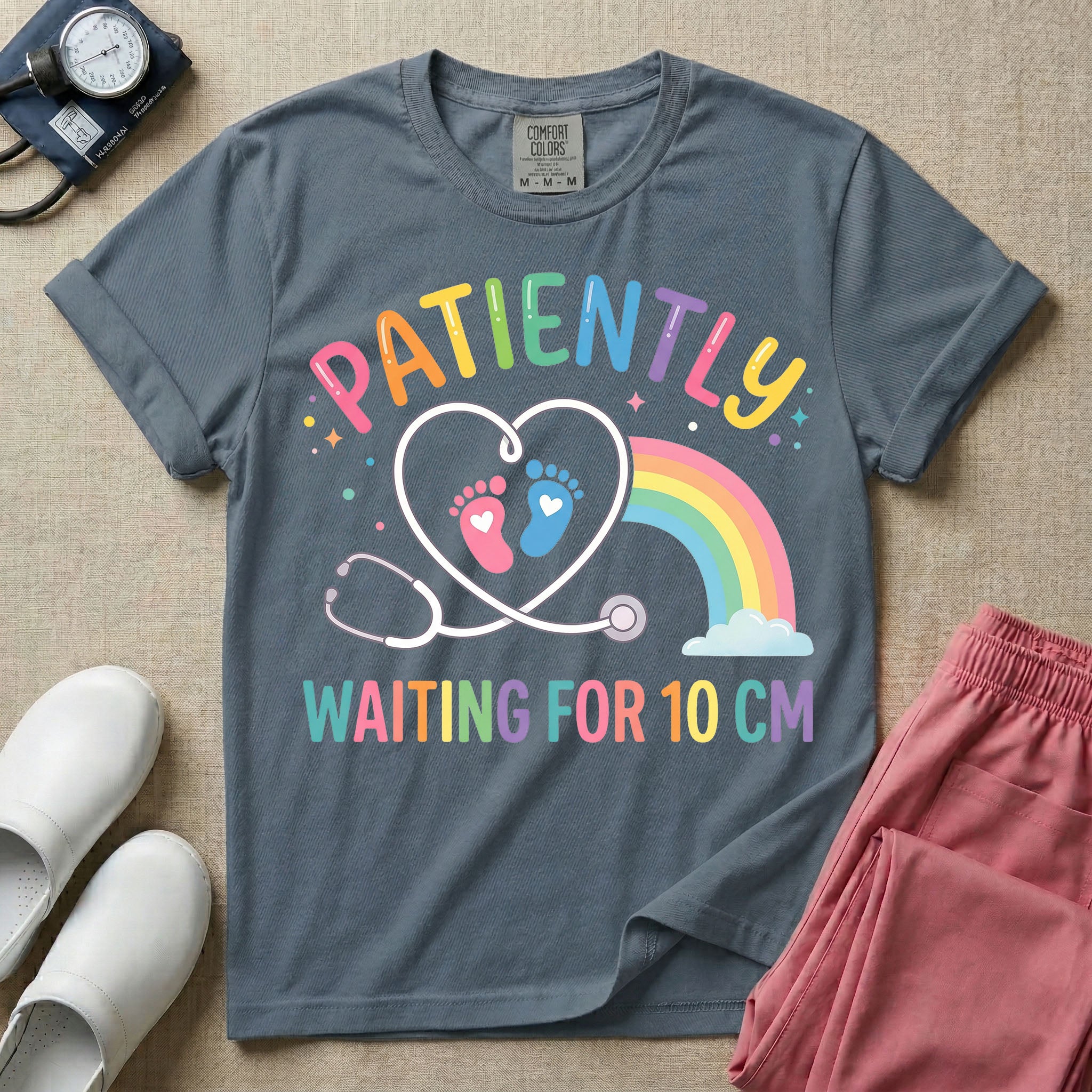 A cute Labor and Delivery and Midwife design featuring a heart-shaped stethoscope enclosing pink and blue baby footprints next to a pastel rainbow and small stars, accompanied by the text "PATIENTLY WAITING FOR 10 CM" in colorful lettering.