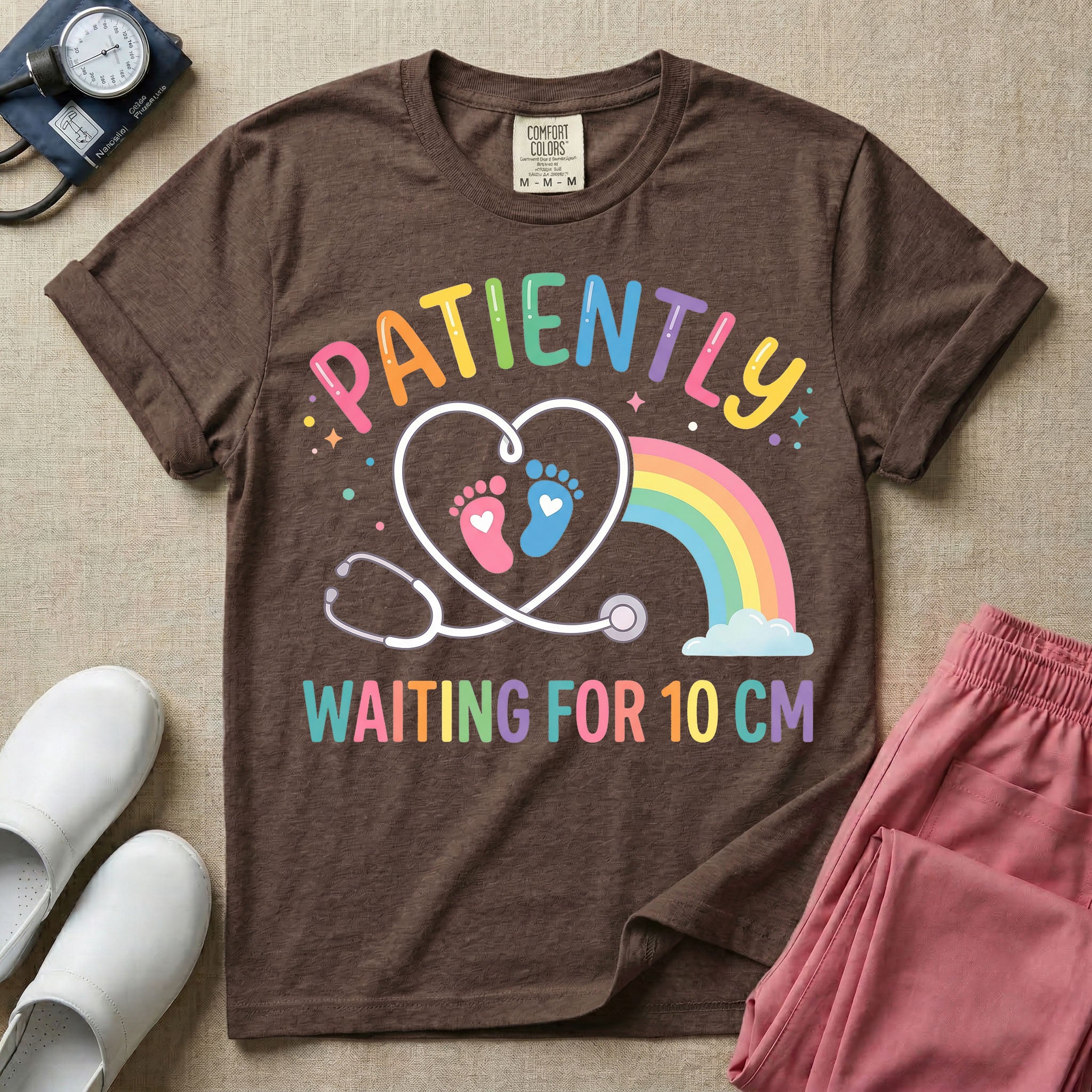 A cute Labor and Delivery and Midwife design featuring a heart-shaped stethoscope enclosing pink and blue baby footprints next to a pastel rainbow and small stars, accompanied by the text "PATIENTLY WAITING FOR 10 CM" in colorful lettering.