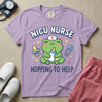 A cute Neonatal Intensive Care Unit nurse design featuring a smiling green frog wearing a nurse hat with a red heart, holding a baby bottle, accompanied by a floating pacifier, safety pin, stars, and hearts, surrounded by the text "NICU NURSE HOPPING TO HELP".