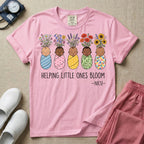 A Neonatal Intensive Care Unit nurse design featuring five peacefully sleeping, diverse babies in differently patterned swaddles with vibrant flowers like sunflowers and daisies blooming from the tops of their heads, positioned above the text "HELPING LITTLE ONES BLOOM -NICU-".