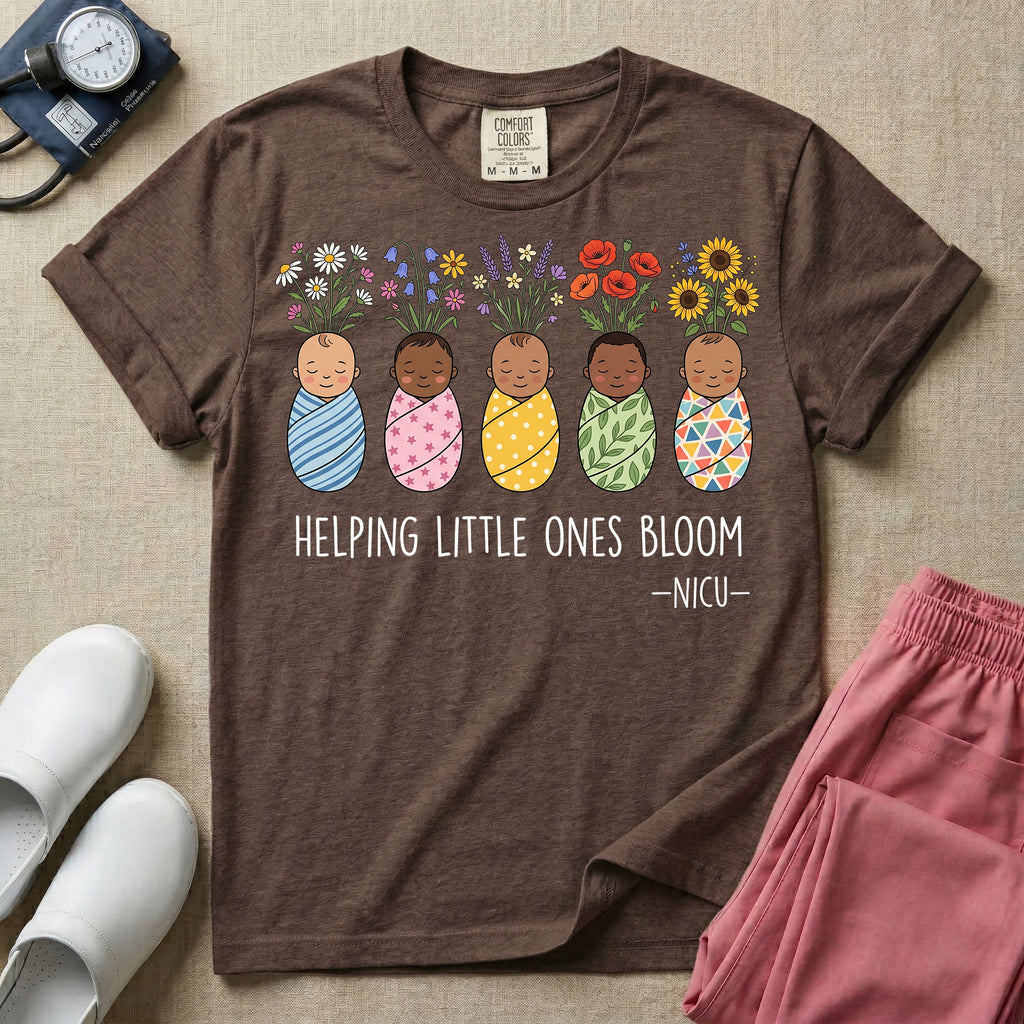 A Neonatal Intensive Care Unit nurse design featuring five peacefully sleeping, diverse babies in differently patterned swaddles with vibrant flowers like sunflowers and daisies blooming from the tops of their heads, positioned above the text "HELPING LITTLE ONES BLOOM -NICU-".