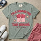 A retro Neonatal Intensive Care Unit nurse design featuring two crossed heart-shaped lollipops over a textured pink square, flanked by two baby pacifiers, sparkling stars, and small hearts, surrounded by the humorous text "I'M A SUCKER FOR TINY HUMANS NICU Crew" in a red and pink groovy font.