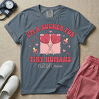 A retro Neonatal Intensive Care Unit nurse design featuring two crossed heart-shaped lollipops over a textured pink square, flanked by two baby pacifiers, sparkling stars, and small hearts, surrounded by the humorous text "I'M A SUCKER FOR TINY HUMANS NICU Crew" in a red and pink groovy font.