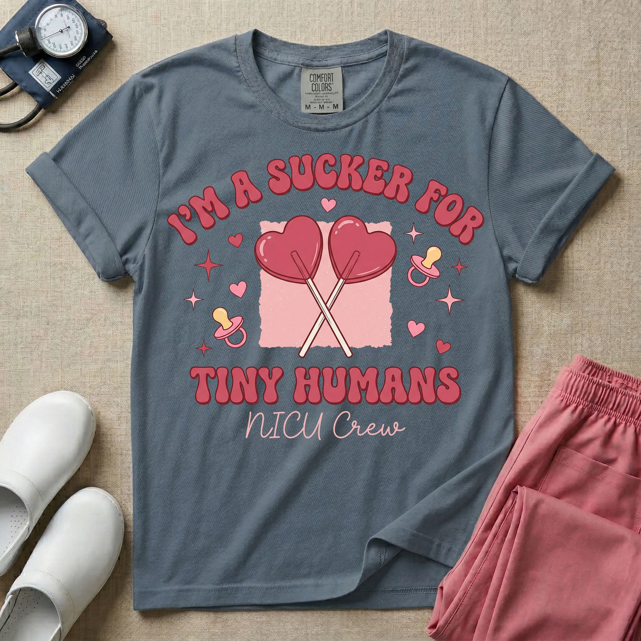 A retro Neonatal Intensive Care Unit nurse design featuring two crossed heart-shaped lollipops over a textured pink square, flanked by two baby pacifiers, sparkling stars, and small hearts, surrounded by the humorous text "I'M A SUCKER FOR TINY HUMANS NICU Crew" in a red and pink groovy font.