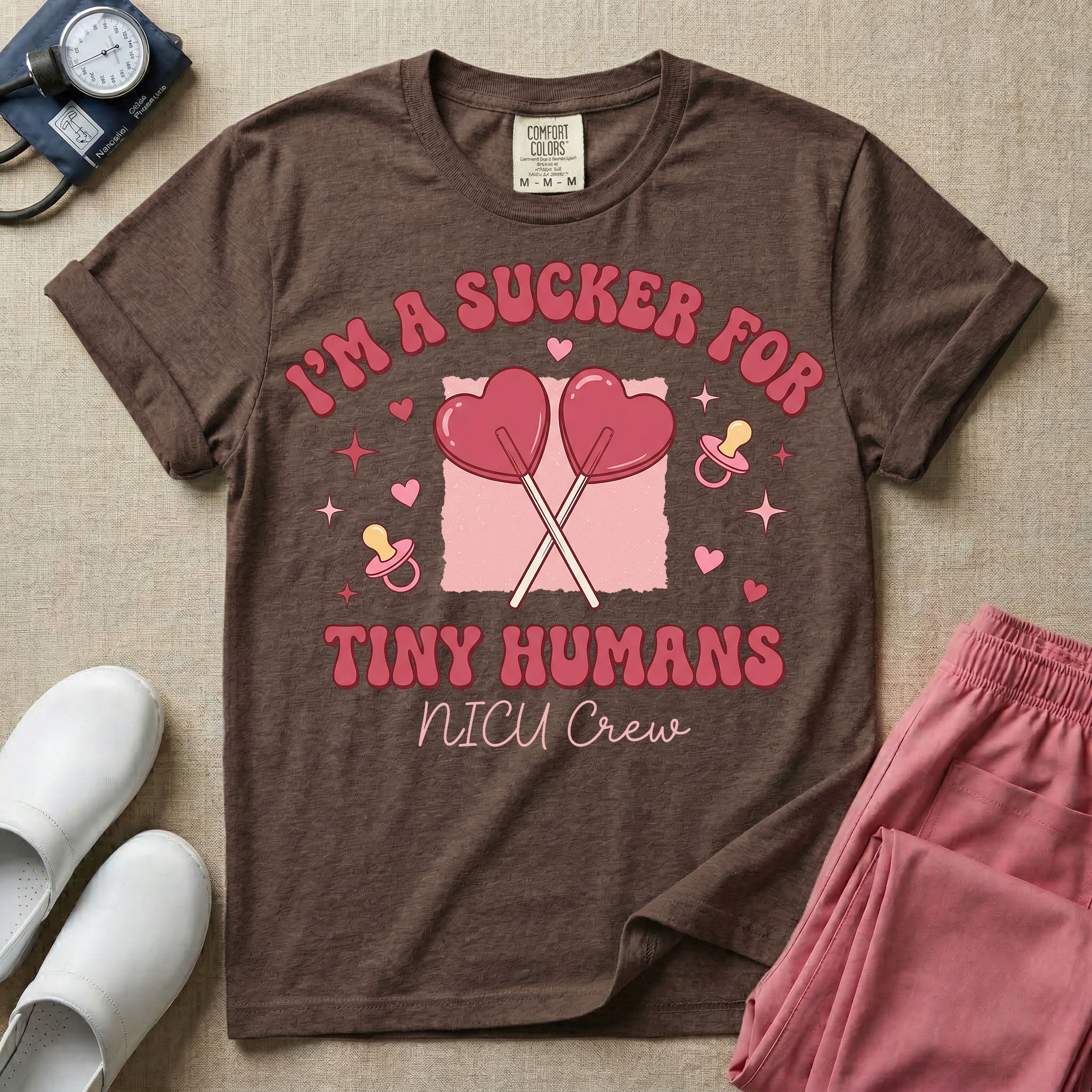 A retro Neonatal Intensive Care Unit nurse design featuring two crossed heart-shaped lollipops over a textured pink square, flanked by two baby pacifiers, sparkling stars, and small hearts, surrounded by the humorous text "I'M A SUCKER FOR TINY HUMANS NICU Crew" in a red and pink groovy font.
