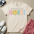A retro Neonatal Intensive Care Unit nurse design featuring the word "NEONATAL" in simple white lettering above the word "NURSE" spelled out in large, distressed, pastel-colored letters, with a classic yellow smiley face replacing the letter U.