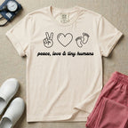 A t-shirt featuring minimalist line art of a peace sign, a heart, and baby footprints above the text "peace, love & tiny humans" designed for NICU, labor and delivery, and pediatric nurses.