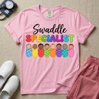 A graphic featuring the word Swaddle in white cursive above the word SPECIALIST in bright, colorful bubble letters, resting over a row of eight diverse babies wrapped in colorful patterned swaddles, designed for NICU, labor and delivery, postpartum, and pediatric nurses.