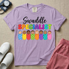 A graphic featuring the word Swaddle in white cursive above the word SPECIALIST in bright, colorful bubble letters, resting over a row of eight diverse babies wrapped in colorful patterned swaddles, designed for NICU, labor and delivery, postpartum, and pediatric nurses.