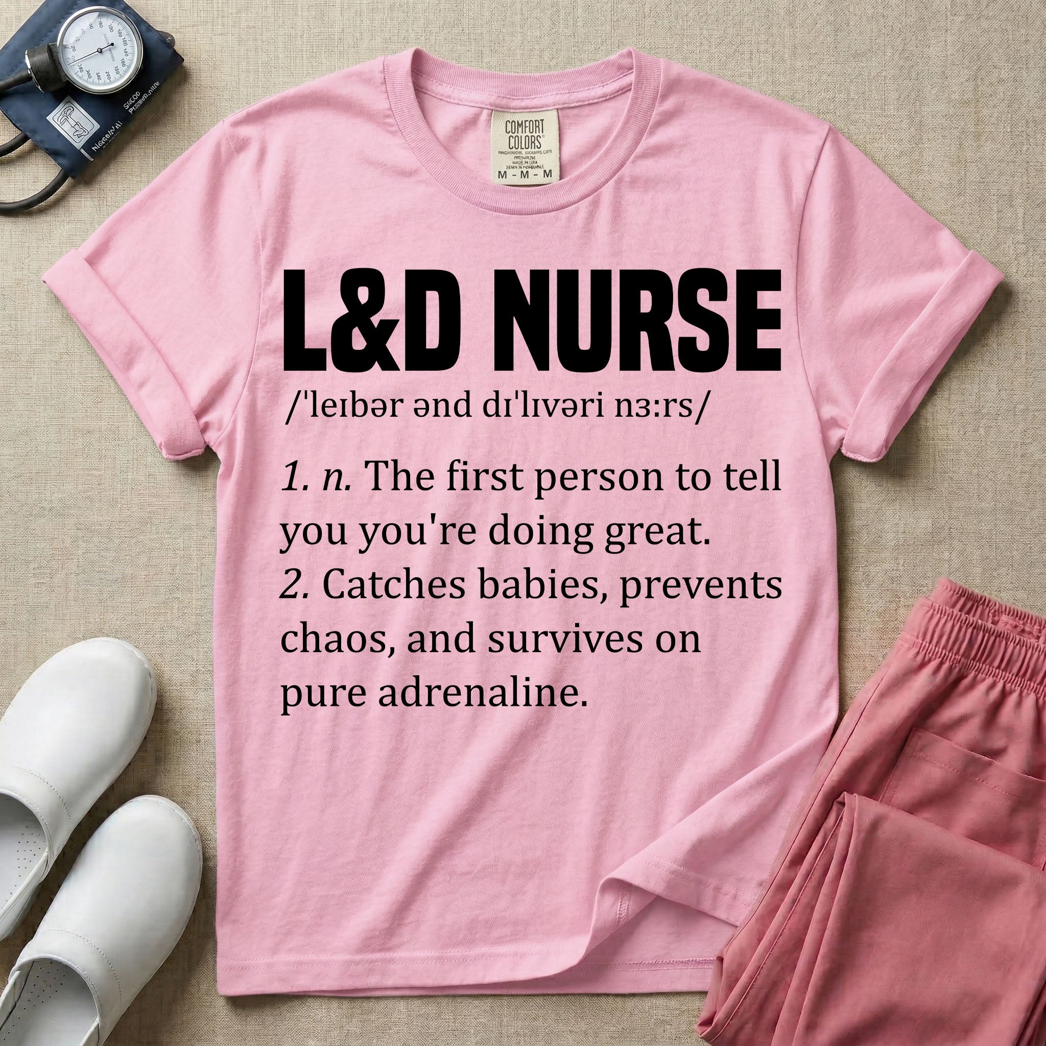 A graphic featuring a dictionary definition style layout with the bold heading L&D NURSE, followed by the phonetic pronunciation and two humorous definitions reading "1. n. The first person to tell you you're doing great." and "2. Catches babies, prevents chaos, and survives on pure adrenaline." in white text, designed for labor and delivery nurses.