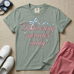 A graphic featuring the phrase "Delivering miracles daily" in elegant pink cursive script, topped with a delicate light blue ribbon bow and surrounded by sparkling stars, designed for labor and delivery, postpartum, and NICU nurses.