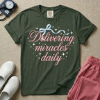 A graphic featuring the phrase "Delivering miracles daily" in elegant pink cursive script, topped with a delicate light blue ribbon bow and surrounded by sparkling stars, designed for labor and delivery, postpartum, and NICU nurses.
