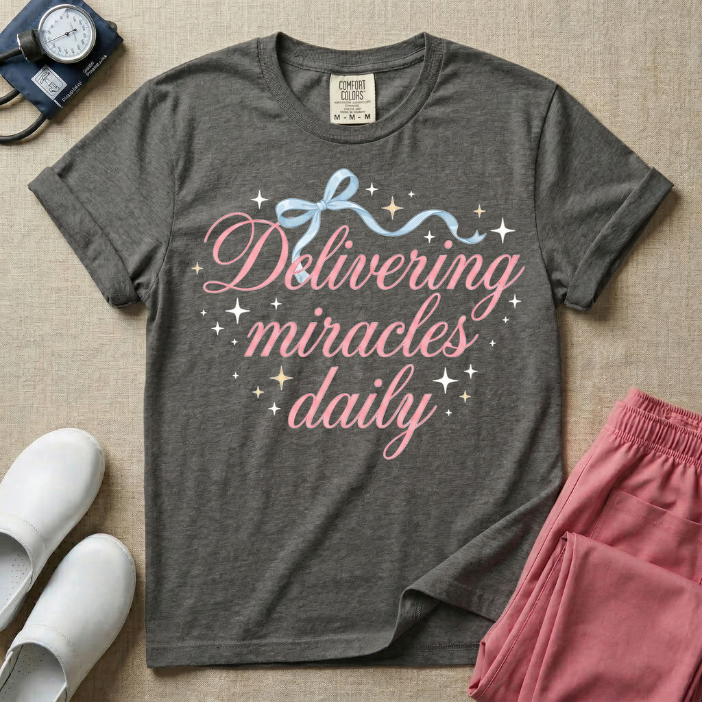 A graphic featuring the phrase "Delivering miracles daily" in elegant pink cursive script, topped with a delicate light blue ribbon bow and surrounded by sparkling stars, designed for labor and delivery, postpartum, and NICU nurses.