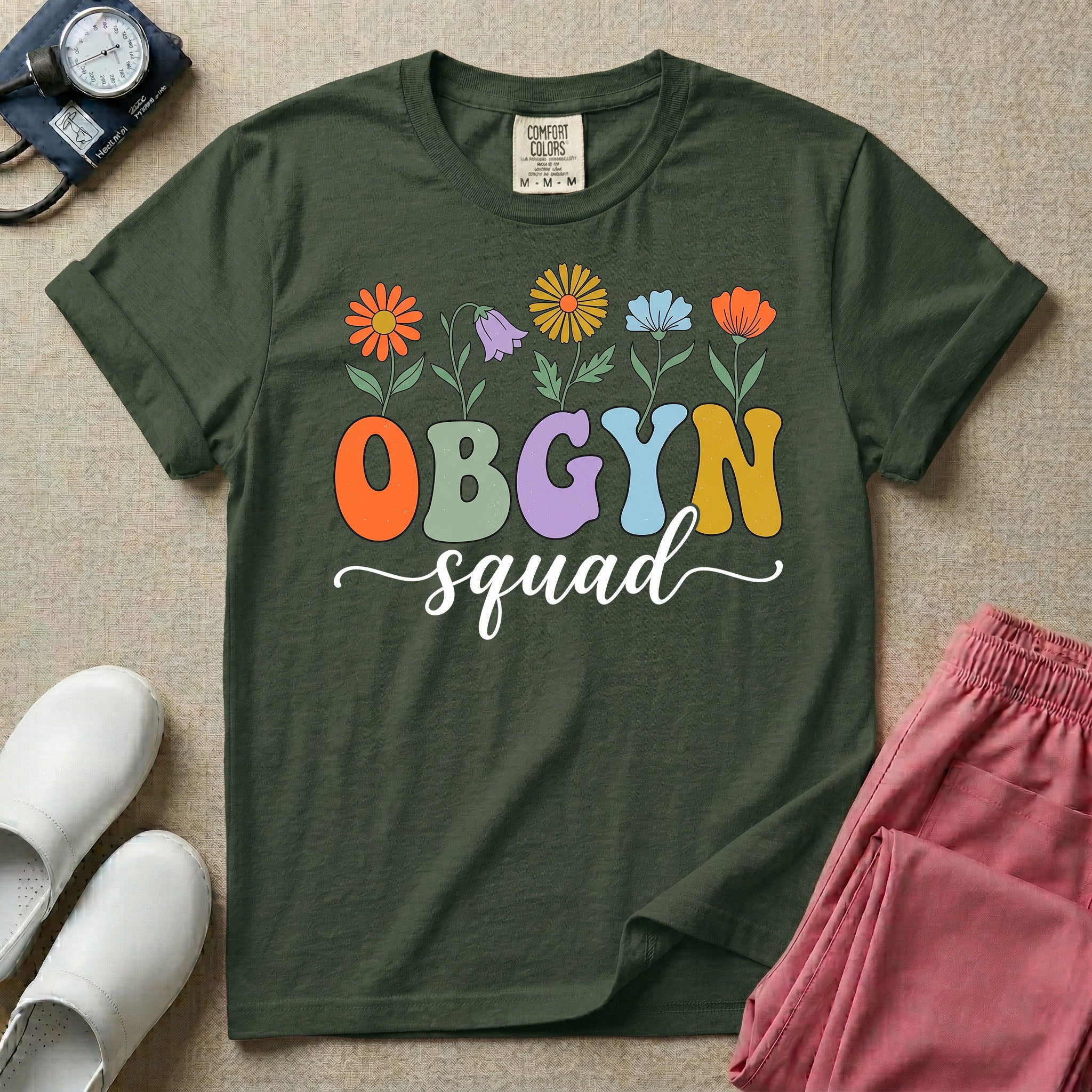 A retro floral graphic design for an OB-GYN unit featuring colorful retro flowers growing out of the letters OBGYN, with the word squad written below in a white cursive script.