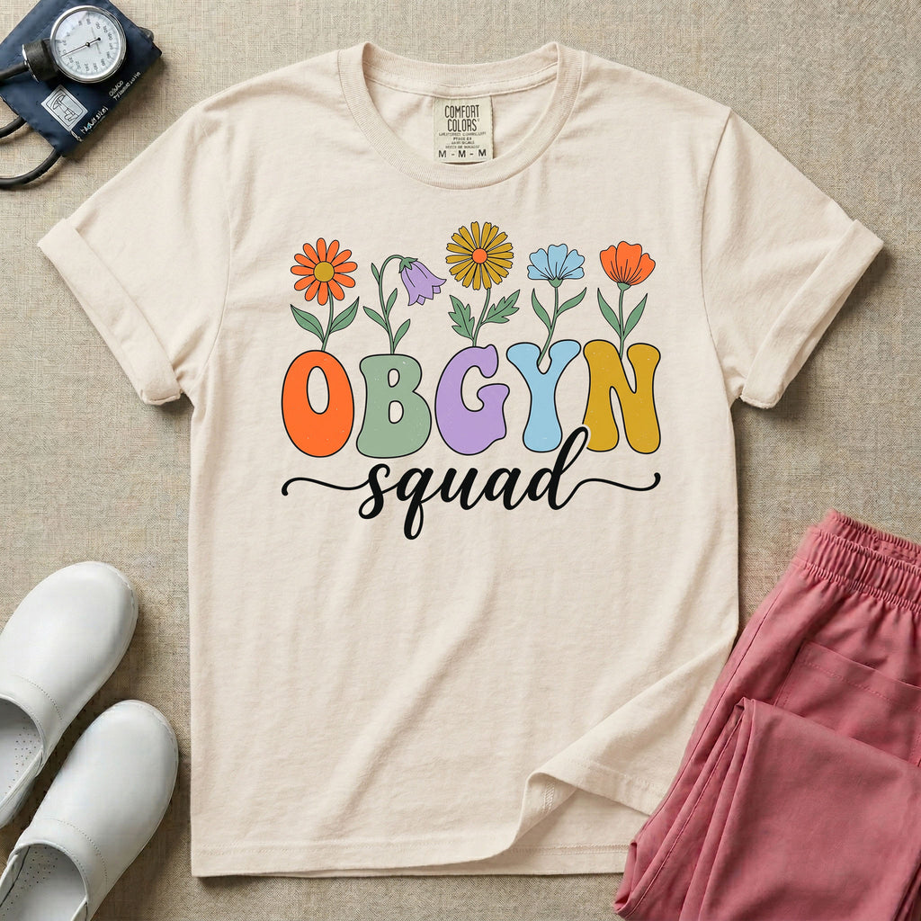 A retro floral graphic design for an OB-GYN unit featuring colorful retro flowers growing out of the letters OBGYN, with the word squad written below in a white cursive script.