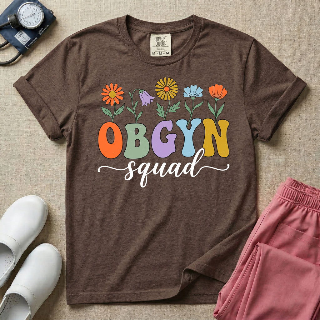 A retro floral graphic design for an OB-GYN unit featuring colorful retro flowers growing out of the letters OBGYN, with the word squad written below in a white cursive script.