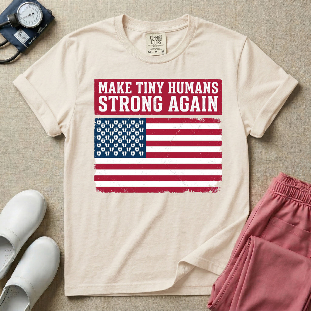 A patriotic graphic design for NICU nursing featuring the text MAKE TINY HUMANS STRONG AGAIN in white block letters against a distressed red background, positioned above a vintage American flag where the traditional stars have been replaced by rows of tiny white baby footprints.