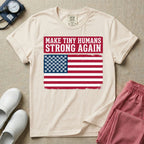 A patriotic graphic design for NICU nursing featuring the text MAKE TINY HUMANS STRONG AGAIN in white block letters against a distressed red background, positioned above a vintage American flag where the traditional stars have been replaced by rows of tiny white baby footprints.
