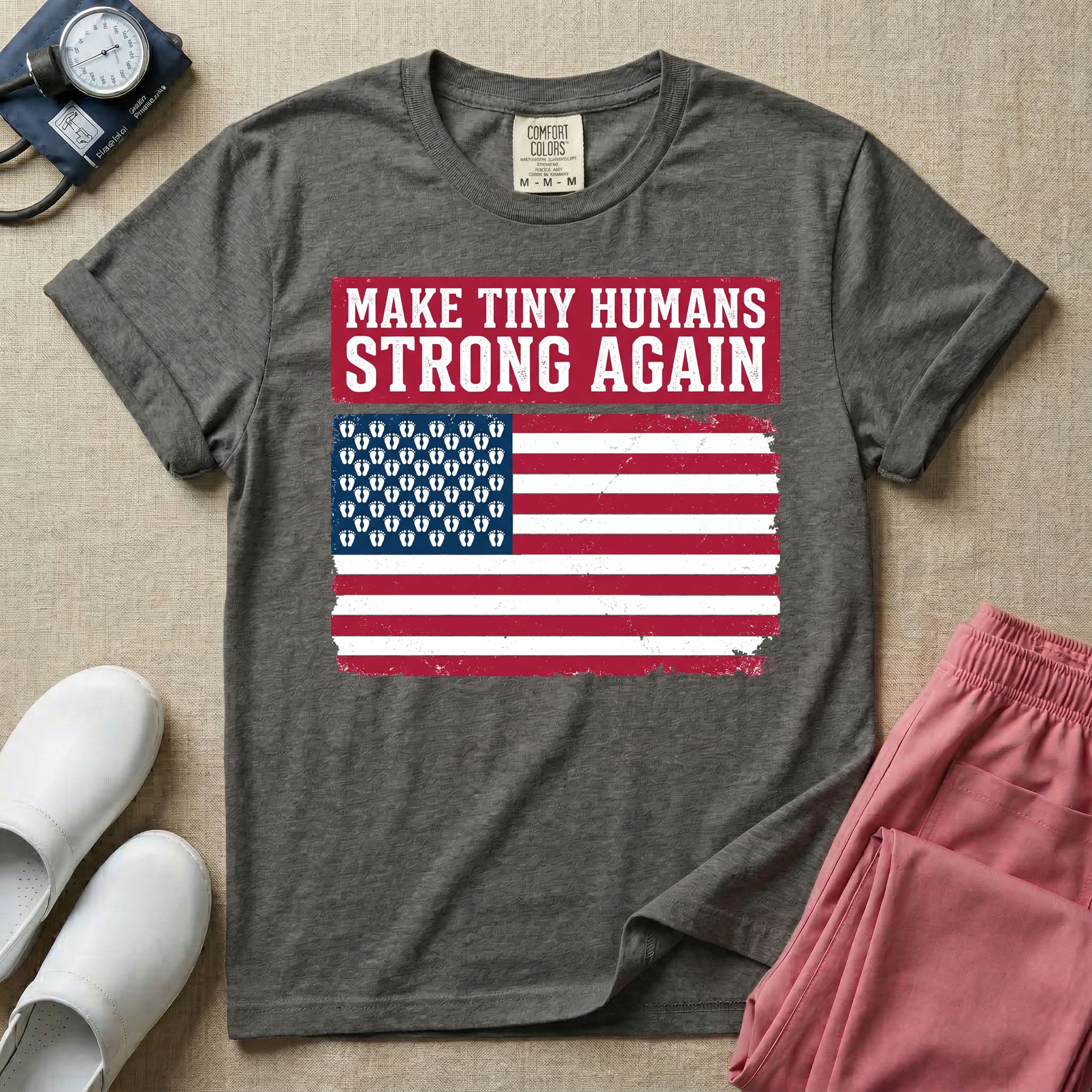 A patriotic graphic design for NICU nursing featuring the text MAKE TINY HUMANS STRONG AGAIN in white block letters against a distressed red background, positioned above a vintage American flag where the traditional stars have been replaced by rows of tiny white baby footprints.