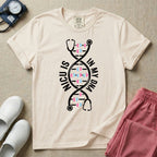 A graphic design for NICU nursing featuring a white DNA double helix structure intertwined with a stethoscope, where the rungs of the DNA strand are made of tiny pink and blue baby footprints, accompanied by the text NICU IS on the left and IN MY DNA on the right.