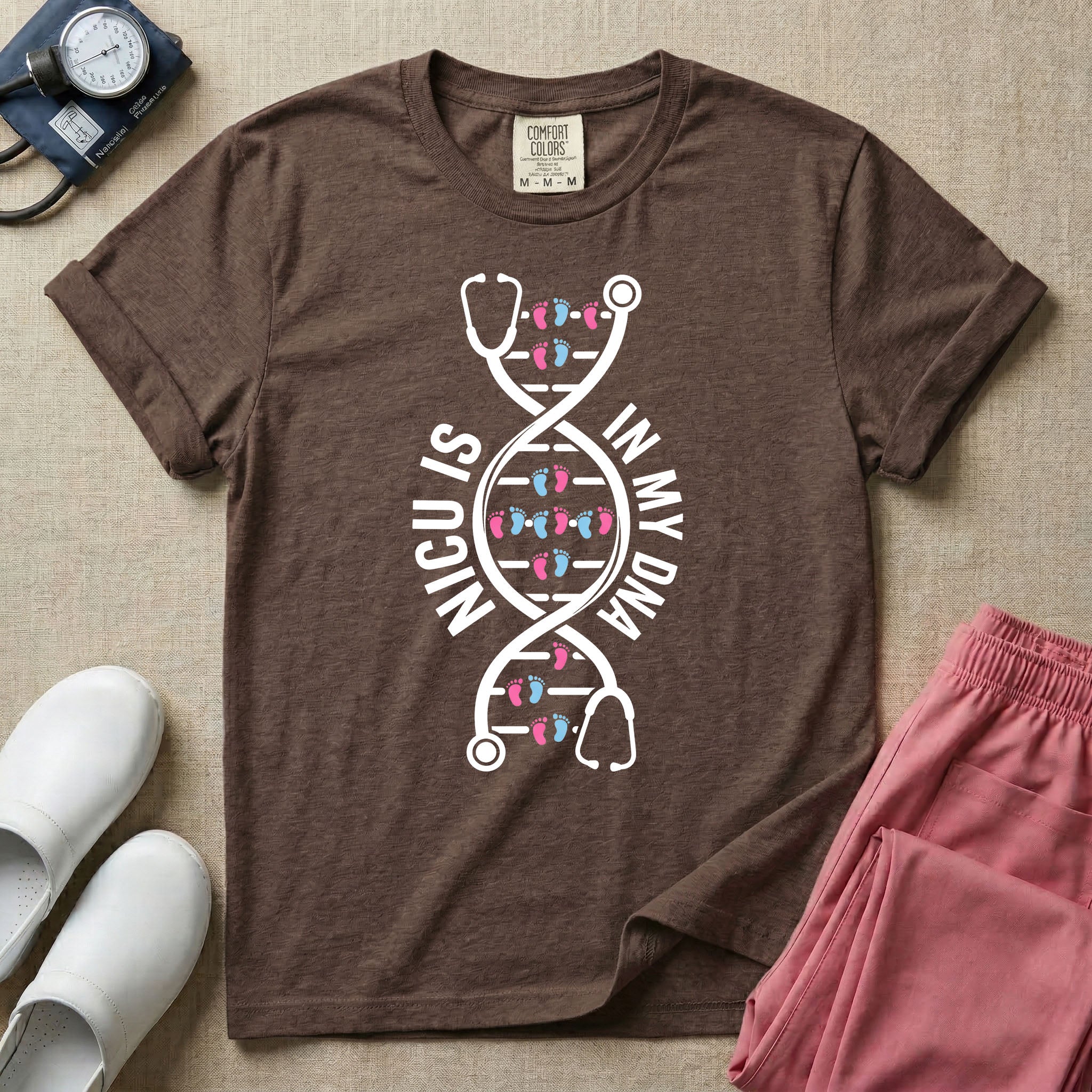 A graphic design for NICU nursing featuring a white DNA double helix structure intertwined with a stethoscope, where the rungs of the DNA strand are made of tiny pink and blue baby footprints, accompanied by the text NICU IS on the left and IN MY DNA on the right.