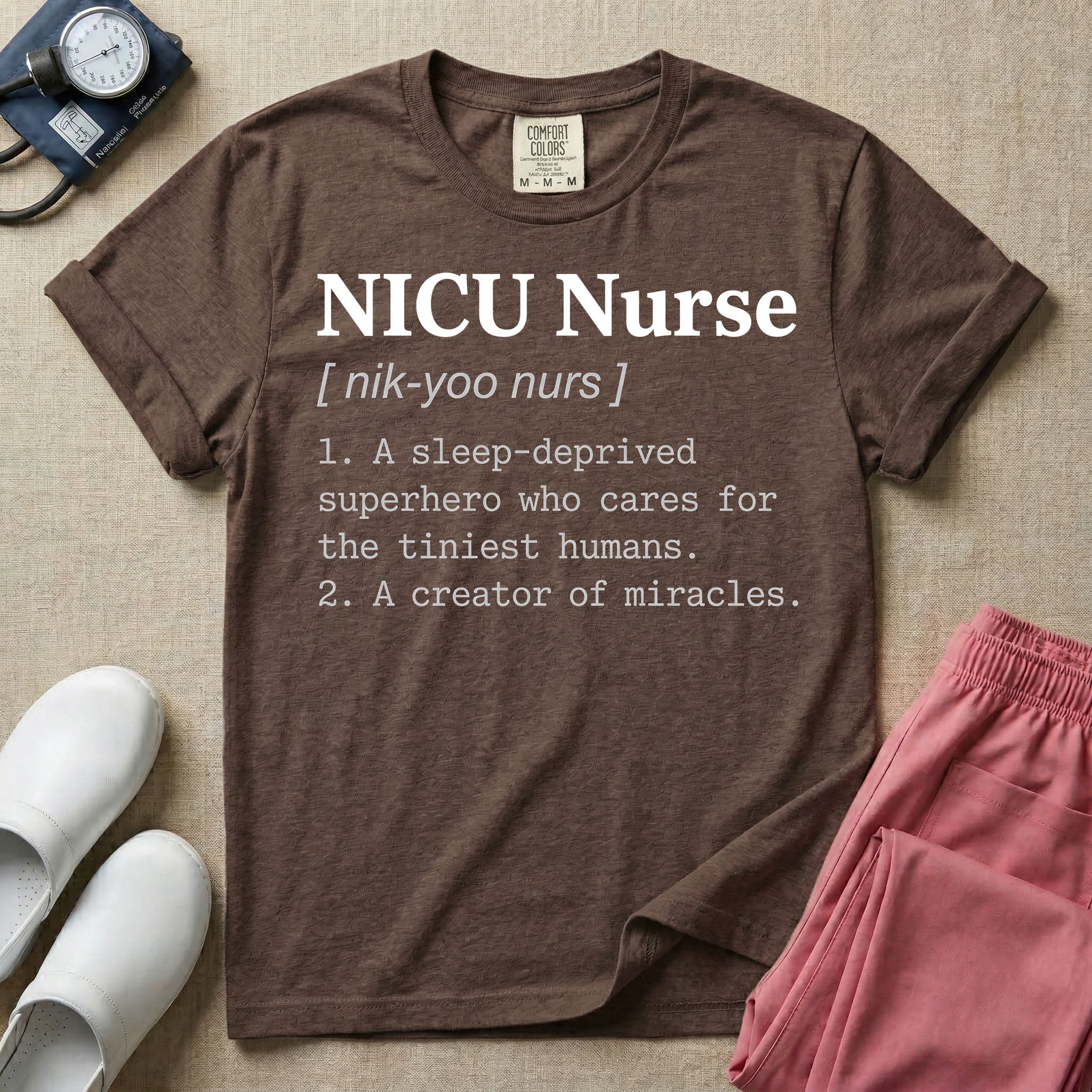 A minimalist neonatal intensive care unit t-shirt featuring a funny dictionary definition graphic that reads "NICU Nurse [ nik-yoo nurs ] 1. A sleep-deprived superhero who cares for the tiniest humans. 2. A creator of miracles."
