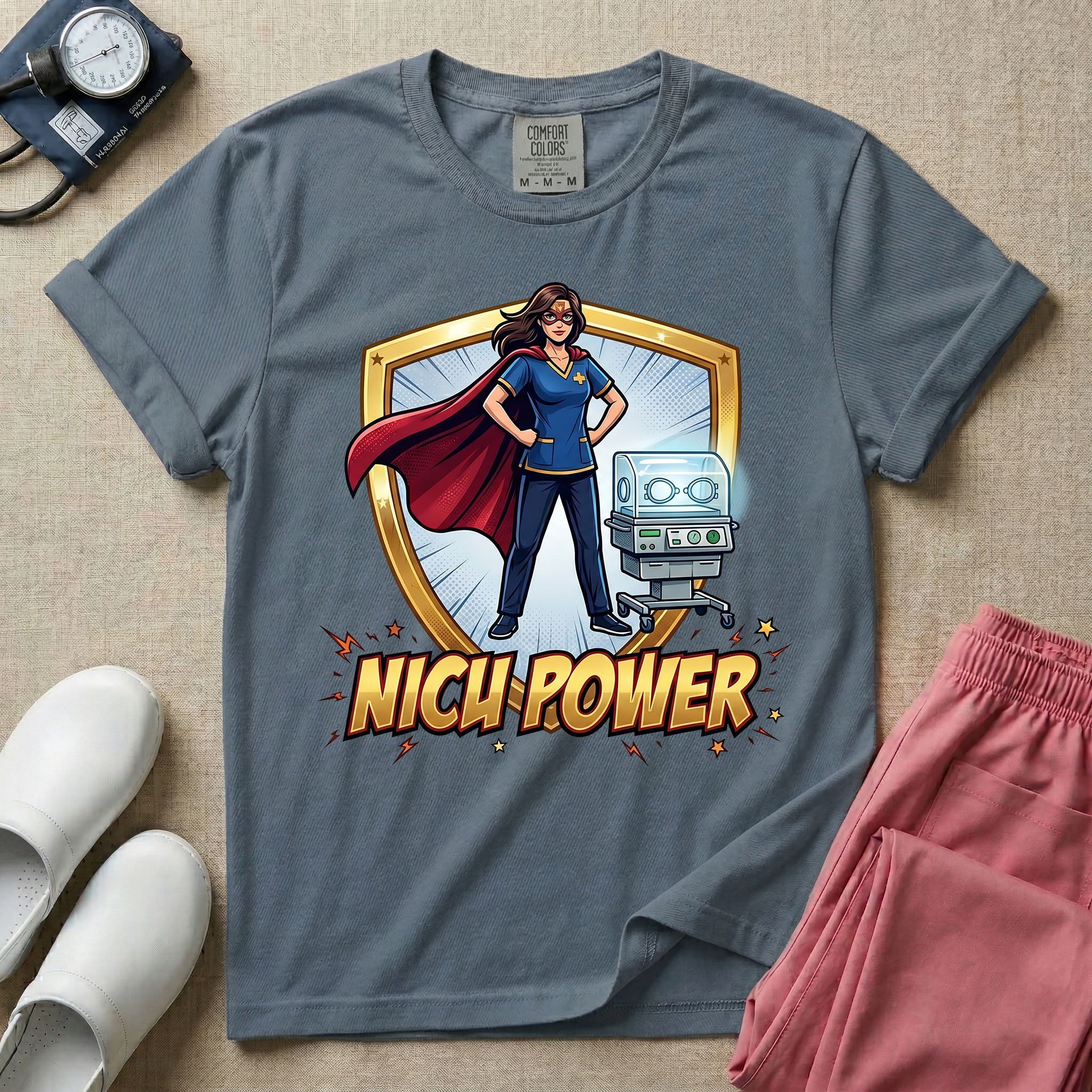 A comic book style neonatal intensive care unit t-shirt featuring an illustration of a confident female nurse wearing a red superhero cape and mask, standing next to an infant incubator inside a golden shield, with the bold text "NICU POWER" below.