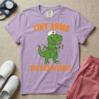 A funny neonatal intensive care unit t-shirt featuring an illustration of a green T-Rex dinosaur wearing a nurse cap and stethoscope, juggling a baby bottle and pacifiers, surrounded by distressed orange text that reads "TINY ARMS" at the top and "BIG NICU HEARTS" at the bottom.
