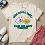 A funny neonatal intensive care unit t-shirt featuring an illustration of a purple sleep mask with Zs next to a yellow infant incubator with a baby inside, surrounded by the text "WHO NEEDS SLEEP WHEN YOU HAVE THE NICU" in a bold teal font.