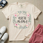 A t-shirt featuring a boho floral wreath composed of pink and cream roses intertwined with a stethoscope, surrounding the text NICU MAMA in elegant typography.
