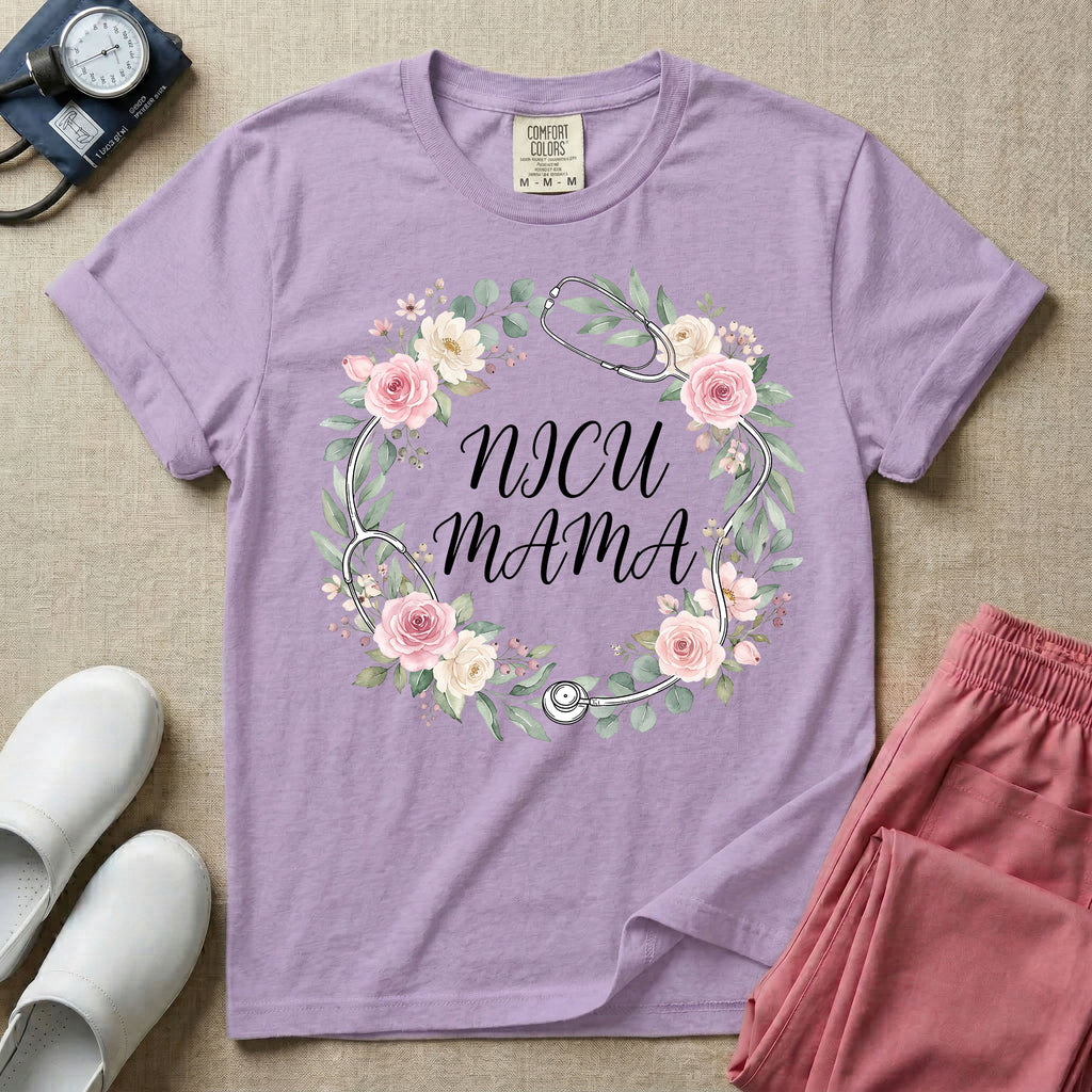A t-shirt featuring a boho floral wreath composed of pink and cream roses intertwined with a stethoscope, surrounding the text NICU MAMA in elegant typography.